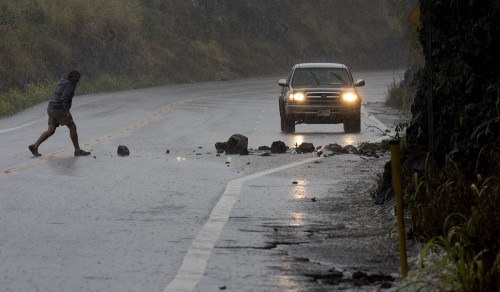 20081226_lapahoehoe-rockslide A motorist stops at Laupahoehoe Gulch to clear the Hilo bound lane of a rockslide as heavy rains hit the east side of the Big Island.