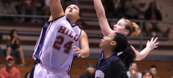 Hilo's Sheila Azevedo lays up the ball beyond the reach of NDNU's #23 Jennifer Dreessen and #32 Tanaia Keyes.