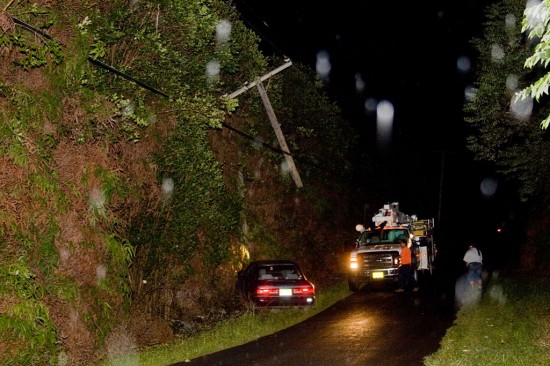 20090714_accident-vehicle A utility pole dangles from high power lines resting on treetops after being severed by a car. White slotches on the photo are due to rain illuminated by camera flash. Photography by Baron Sekiya/Hawaii247.com