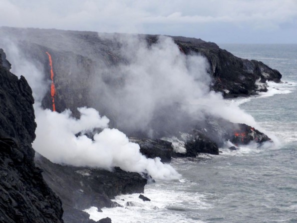 20111213_usgs-lava-down-cliff1 The current lava flow, coming down the pali and traversing the coastal plain, reached the ocean late last week. The ocean entry point is within the National Park, near its eastern border. Today, numerous small streams of lava were cascading over the sea cliff, and lava entering the water was starting to build a small delta. Photo courtesy of USGS/HVO