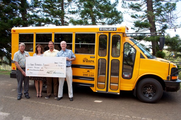 HPA-FHB-Grant Harold Hughes (left), vice president and area manager at First Hawaiian Bank - Kamuela Branch, and Vicki Hasty, vice president of First Hawaiian Bank Business Banking and Team Leader West Side of the Island of Hawaii, present a check to Hawaii Preparatory Academy's Keawe Liu, assistant headmaster for external relations, and Lindsay Barnes (right), headmaster. The group is pictured in front of one of the school's two new buses purchased with grant funds from the First Hawaiian Bank Foundation.