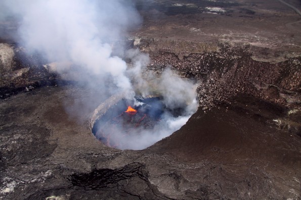South winds permitted clear views into the south portion of the Overlook crater, which is often obscured by thick fume. The bright orange area is the location where lava at the surface of the lake sinks back into the system, with spattering and degassing common in this area. A broad ledge of recently deposited lava occupies much of the south portion of the crater. Photo courtesy of USGS/HVO