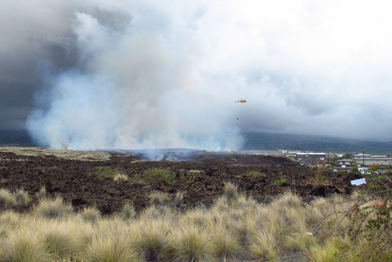A helicopter makes a water drop on a brush fire near Kohanaiki. (Hawaii 24/7 photo by Andrew Cooper)