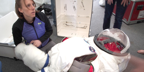 The HI-SEAS training included preparations for donning a simulated space suit, for use during excursions from the habitat. Here, crew member Tiffany Swarmer makes some adjustments with the suit. (Photo courtesy of Ross Lockwood)