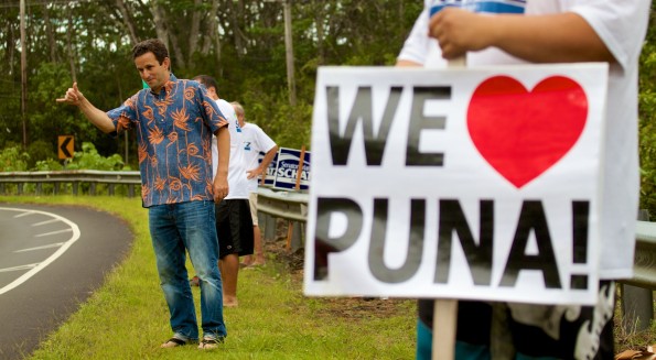 Senator Brian Schatz flashes a shaka sign to passing motorists near Keonepoko Elementary School where two Puna precincts held their delayed primary election polls. Photography by Baron Sekiya | Hawaii 24/7