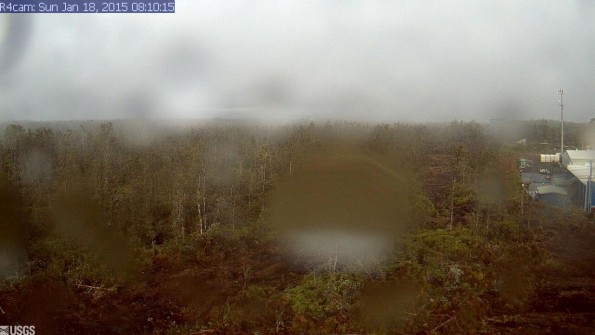 A photo looking west from a research camera temporarily positioned southeast of the Pāhoa Marketplace, this image shows the June 27th lava flow advancing from left to right. The image was taken at 8:10 a.m. Sunday, January 18, 2015. This camera that took this was installed through a collaboration between the USGS Hawaiian Volcano Observatory, Oceanic Time Warner Cable, and Bryson's Cinders Inc.