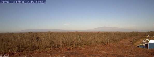 A photo looking west from a research camera temporarily positioned southeast of the Pāhoa Marketplace, this image shows the June 27th lava flow advancing from left to right. Activity is very low so you can see Mauna Loa and Mauna Kea in the distance. The image was taken at 8:40 a.m. Tuesday, February 3, 2015. This camera that took this was installed through a collaboration between the USGS Hawaiian Volcano Observatory, Oceanic Time Warner Cable, and Bryson's Cinders Inc.