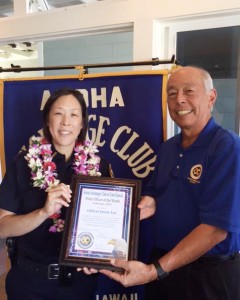 Aloha Exchange board member Joey Estrella presents an 'Officer of the Month' award to Officer Jenny Lee.