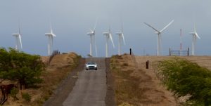 A car makes its way down South Point Road with a backdrop of the Pakini Nui Wind Farm. Hawaii 24/7 File Photo