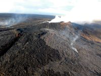 The two new flows that broke out on the flanks of the Puʻu ʻŌʻō cone on Kīlauea Volcano's East Rift Zone on May 24 remained active early the morning of Friday, May 27, 2016. The flows were spreading laterally near the vent, but making little forward progress; as a result, they were not posing a threat to any community. The silvery sheen of new lava erupting from the northern breakout (center) and eastern breakout (far left) stands out in contrast to the older flows on and around Puʻu ʻŌʻō. Photo taken Friday, May 27, 2016 courtesy of USGS/HVO