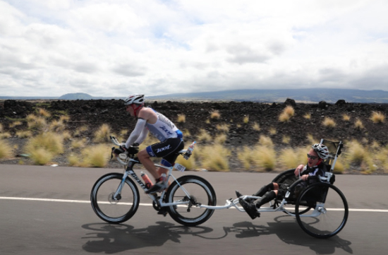Jeff Agar pulls his son, Johnny, who suffers with cerebral palsy, along the bike course. (Photo courtesy of Ironman)