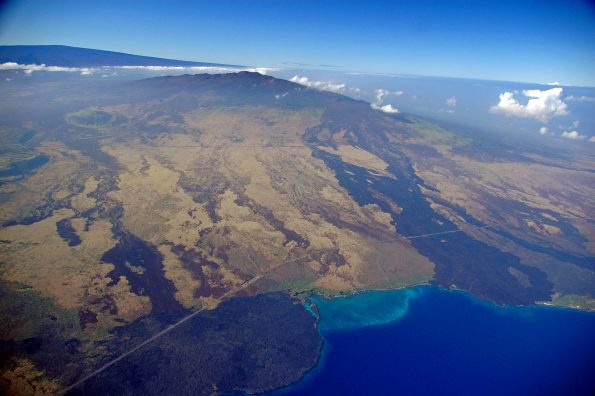 Hualālai (center) and Mauna Loa (left background), two of the four active volcanoes on the Island of Hawaiʻi, are ranked as “high threat” and “very high threat” volcanoes, respectively. Kīholo Bay (right foreground) is flanked on the north (left) by a lava flow erupted from Mauna Loa in 1859 and on the south by the Ka‘ūpūlehu flow erupted from Hualālai around 1800. Photo courtesy of USDA Forest Service.