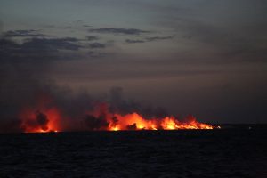 Nighttime scene from shipboard of lava entering the Pacific Ocean on July 12, 2018, captured from a scientific research vessel deploying submarine seismometers. Photograph courtesy of Jackie Caplan-Auerbach, Western Washington University.