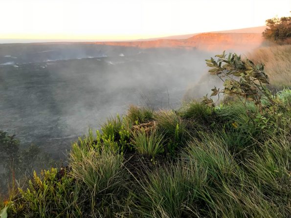 A midwinter dawn at Halemaʻumaʻu on Kīlauea. Steaming cracks tell of water and heat interacting beneath the summit caldera of the volcano. In the background, the first rays of sunlight illuminate Uēkahuna Bluff. USGS photo by E. F. Younger, December 2018.