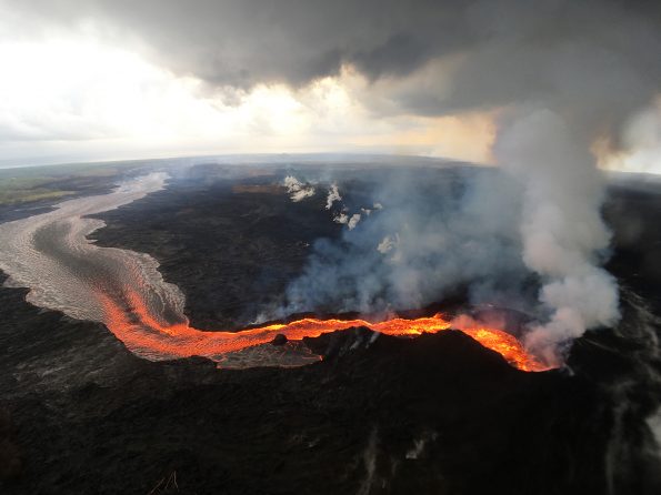During the first two weeks of Kīlauea Volcano’s 2018 lower East Rift Zone eruption, fissures were characterized by low eruption rates and small flows. This was because the erupted lava originated from pockets of cooler, less fluid magma stored in the rift zone. Later fissures erupted hotter, more fluid magma, resulting in higher eruption rates and large, fast-moving lava flows, like that erupted from the fissure 8 cone (lower right), shown here on July 29, 2018. USGS photo by M. Patrick.