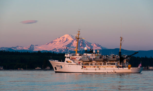 The National Oceanic and Atmospheric Administration Ship Rainier is backdropped by Mount Baker, an active Cascade Range stratovolcano, in Washington. In September 2019, the Rainier conducted a bathymetric survey along Hawaiʻi Island's Puna coast, where lava entered the ocean during Kīlauea Volcano's 2018 eruption. Photo courtesy of NOAA.