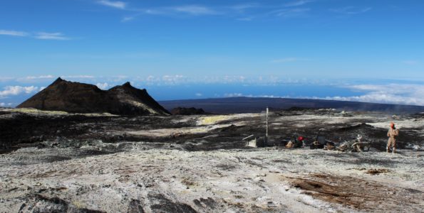 Volcano Watch: High Altitude Station Maintenance on Mauna Loa Sulphur Cone (left), viewed toward southwest, from 3,480 m (11,420 ft) above sea level on Mauna Loa’s southwest rift zone. At right, an HVO geoscientist and technician rebuild volcanic gas monitoring equipment installed near an outgassing fissure.