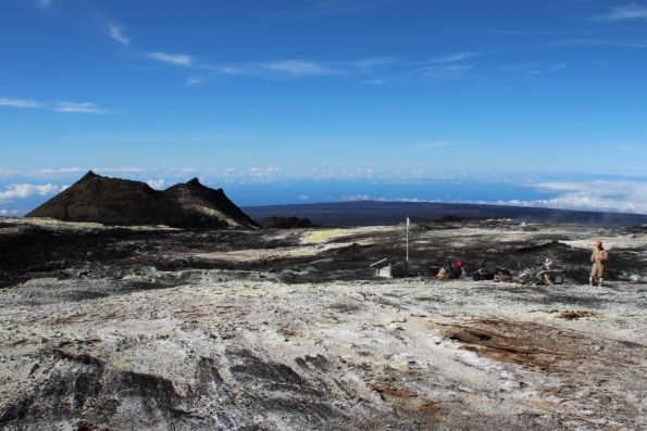 Sulphur Cone (left), viewed toward southwest, from 3,480 m (11,420 ft) above sea level on Mauna Loa’s southwest rift zone. At right, an HVO geoscientist and technician rebuild volcanic gas monitoring equipment installed near an outgassing fissure.